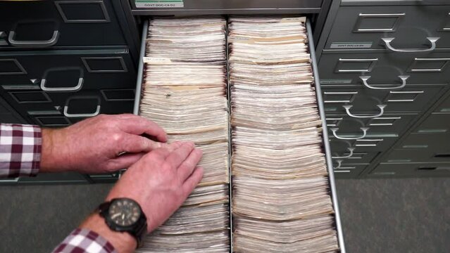 Male Library hands sorting files in a drawer of Microfiche, closeup shot