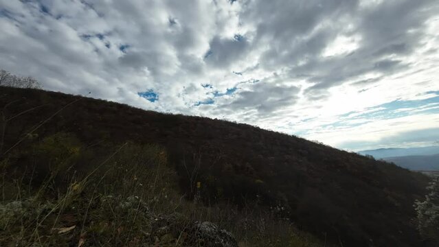 Time lapse landscape footage of sky clouds moving over sloppy green hill