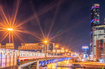 Obraz premium The scyscrapers of the Moscow City at night and the Dorogomilovsky bridge with illumination. Translation of text - street names: Krasnopresnenskaya, center, etc.