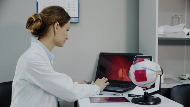 An ophthalmologist sits at a table with various diagnostic devices