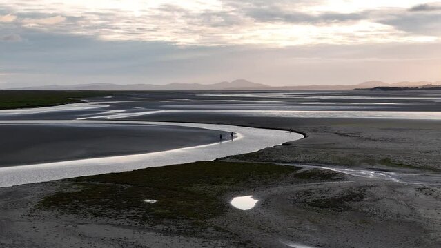 Drone footage of people standing near a calmud flats along Turnagain arm in Alaska at sunset