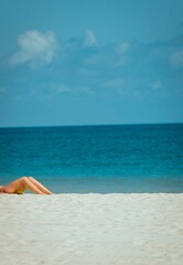 Fototapeta na wymiar Woman lays on a sandy beach at the ocean