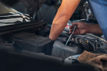 Close up Car Mechanic man hands repairing car auto repair shop. Man hands fixing machinery vehicle...