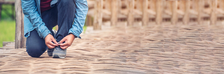 Banner Man kneels down rope tie shoes industry boots for worker. Close up shot of man hands tied...