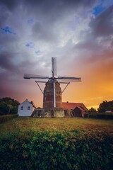 Scenic view of a traditional windmill standing proudly next to a charming white house - obrazy, fototapety, plakaty