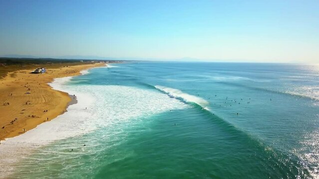 Cinematic aerial drone follow backwards morning crowd of surfers huge waves glassy swell surf  Hossegor Seignosse France yellow sunrise sunset on beach mountain sandy coast Biarritz Basque Country