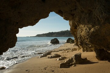 Scenic view of a beach cave entrance looking out onto the serene blue waters of the Atlantic Ocean.