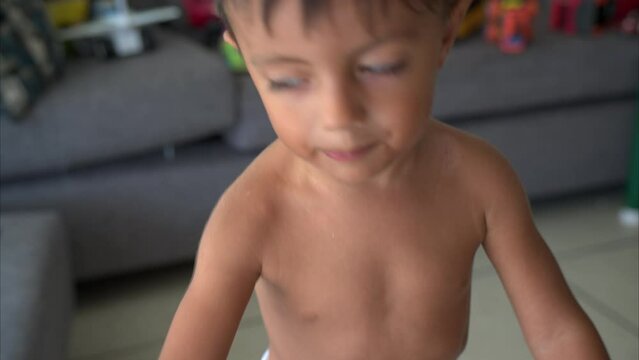 Funny little latin hispanic boy shirtless talking to the camera very expressively