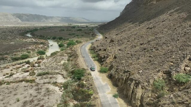 Aerial View Of Vehicle Driving Along Empty Road Through Arid Desert Land At Hingol National Park. Push Forward Shot