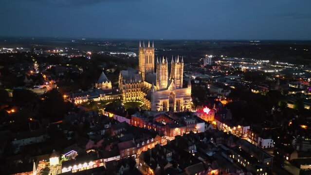 Drone video of Lincoln Cathedral, a UK landmark, at dusk, featuring its majestic, illuminated Gothic architecture.