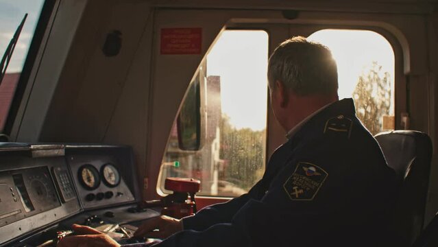 Male old train driver at the control panel in cockpit cab of electric speed train, subway. Public railroad railway transport. Man in uniform test check serviceability of locomotive. Vehicle concept