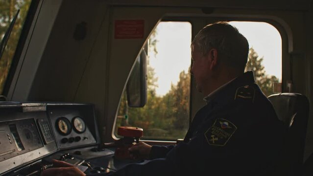 Male old train driver at the control panel in cockpit cab of electric speed train, subway. Public railroad railway transport. Man in uniform test check serviceability of locomotive. Vehicle concept