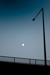 Idyllic nighttime landscape featuring a bridge in the foreground and a crescent moon