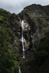 a water fall in the mountains with some trees on either side