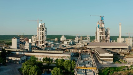 Cement plant with high factory structure at industrial production area at sunset. Aerial drone