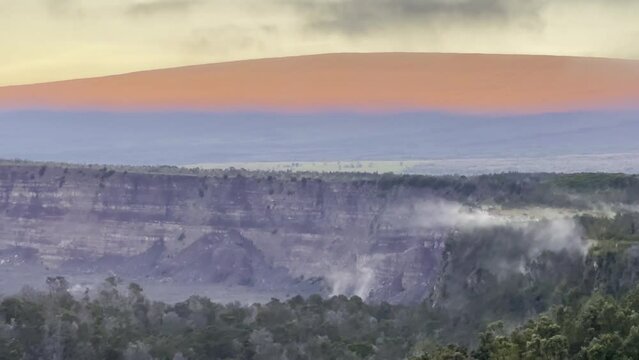 Cinematic long lens booming up shot of Mauna Loa at sunrise from Volcano House in Hawai'i Volcanoes National Park. 4K HDR at 30 FPS