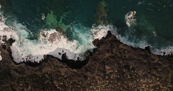 Soaring high above cliffs with volcanoes in the distance as ocean waves crash onto coastline below 
