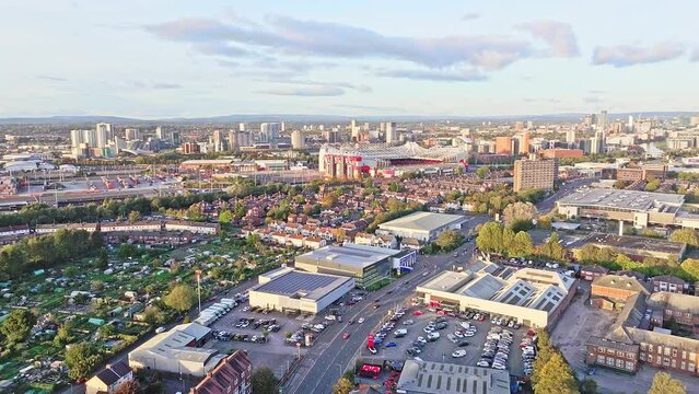 Aerial dolly shot flying away from the Old Trafford stadium in Manchester in landscape format with infrastructure all around.  