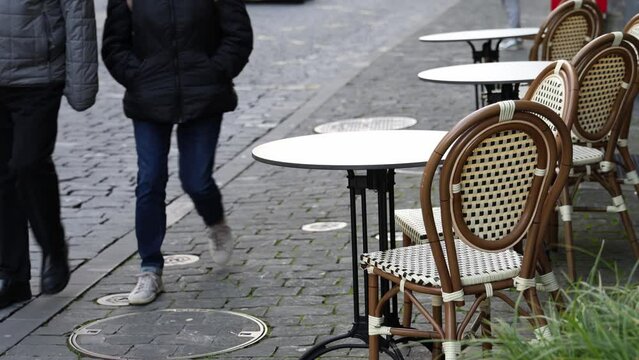 People walking past empty tables and chairs in the restaurant