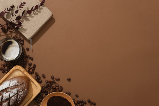 Creative background for advertising and branding product with coffee. Against a brown background, glass cup of coffee, bread and coffee powder decorated on left corner. Space for design