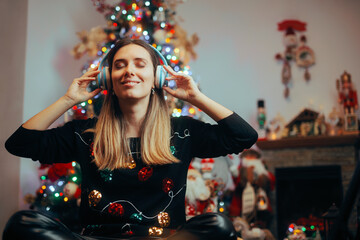 Happy Woman Listening to Christmas Songs at Home. Cheerful girl enjoying Xmas carols alone in her...