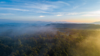 Aerial view of morning sunrise of tropical rainforest at dawn with misty and foggy cloud during summer for outdoor mountain valley landscape