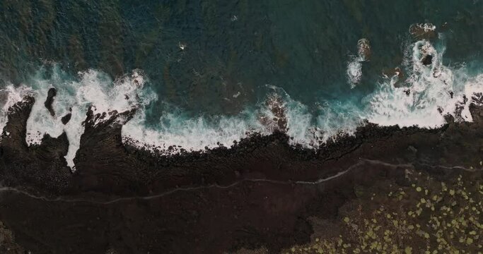 Waves crash onto shoreline as seen from high above creating a beautiful natural texture