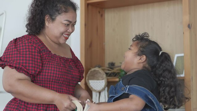 mother and girl are reading a book in living room. Asian chubby family relaxing with education program.