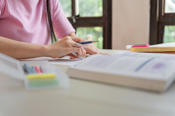 Asian girl student doing exam hand holding pencil writing answer in university classroom education high school or university student taking notes while preparing for exam