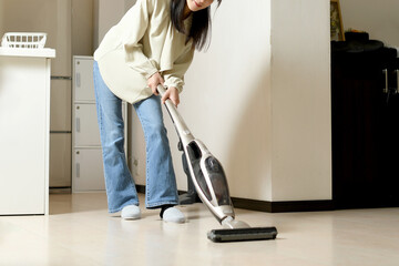 家の中で掃除機をかけるアジア人の若い女性