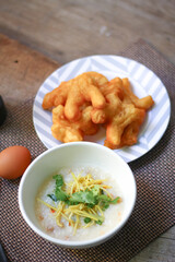 Joke or Congee in a Thai style cup Served on a wooden table. It's an Asian breakfast.
