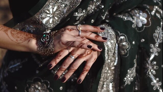 A graceful Indian bride in traditional sari dress displays an intricate Mehndi design on her hands, getting ready for wedding celebration. Beautiful Closeup of authentic cultural fashion. Henna hands