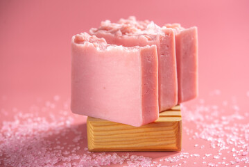 Cute pink pieces of organic eco soap on a soap dish made of natural wood on a pink background. Concept of modern and safe cosmetic products for skin care