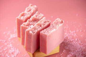 Cute pink pieces of organic eco soap on a soap dish made of natural wood on a pink background....