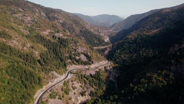 Aerial view road in green mountains with stunning gorge landscape. Drone video