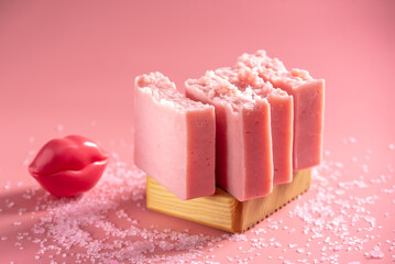 Cute pink pieces of handmade natural soap on a wooden soap dish on a pink background. Modern and safe cosmetic products for skin care and interesting hobby