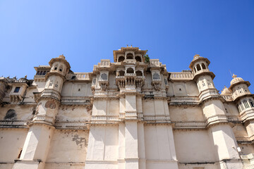 Tall walls of historic City Palace, Udaipur reaching sky.