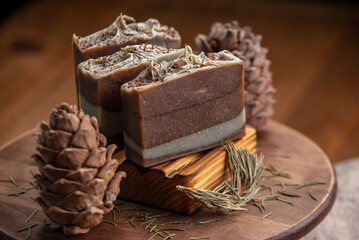 Pieces of natural coniferous soap on a wooden stand surrounded by cones and needles. Concept of organic cosmetics, beautiful atmospheric winter postcard
