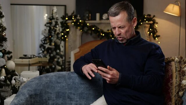 Displeased man reads the bad news on a smartphone. The emotion of shock and surprise. Christmas holiday time
