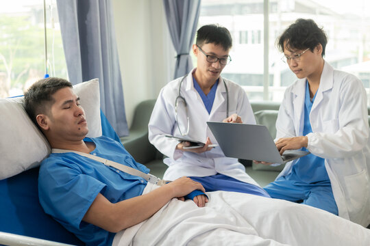 Male patient in a hospital bed with medical staff at the bedside giving encouragement and advice on treatment.