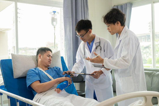 Male patient in a hospital bed with medical staff at the bedside giving encouragement and advice on treatment.