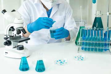 Fototapeta premium Doctor in mask examining DNA molecule in chemistry lab with scientist examining liquid sample with microscope in chemistry lab Researcher working with sample