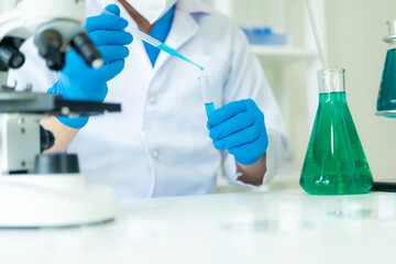 Fototapeta premium Doctor in mask examining DNA molecule in chemistry lab with scientist examining liquid sample with microscope in chemistry lab Researcher working with sample
