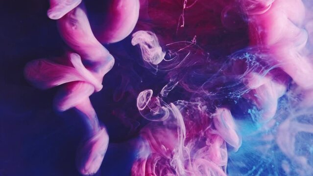 Vertical video. Ink splash background. Mysterious illusion. Pink smoke cloud puff colorful creative hypnotic swirls spreading effect in blue abstract steam art.