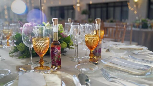 Decoration of wedding table with flowers, glasses and gift wine. Slow rotation camera movement.