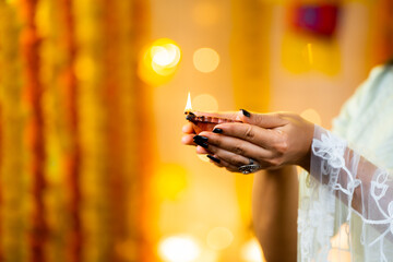 Close up shot of indian girl hands holding diya lamp during diwali festival celebration - concept of traditional culture, greeting and spirituality or harmony.