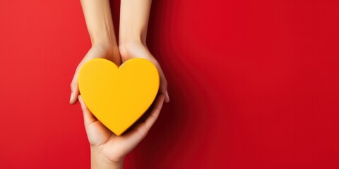 Hands holding heart and gift box on a yellow and red  background, giving love and generosity to loved ones. - obrazy, fototapety, plakaty
