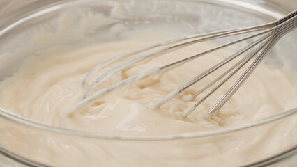 Bowl of white chocolate vanilla bean pudding close-up on a wooden table. Mixing ingredients
