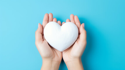 Woman holding white heart on blue background, top view.
