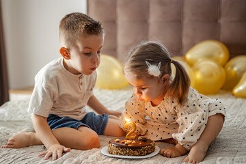 Brother and sister celebrating birthday and blowing candle on a cake.